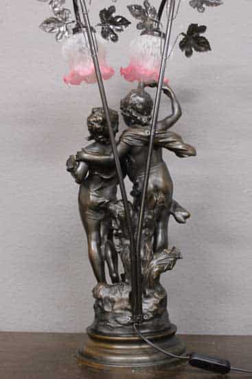 Zauberhafte antike Jugendstil Tischlampe aus Kunstguss zeigt ein junges Paar, welches von zwei Lichtern in außergewöhnlichen Blütenschirmen beleuchtet wird